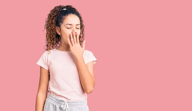Beautiful kid girl with curly hair wearing casual clothes bored yawning tired covering mouth with hand. restless and sleepiness.