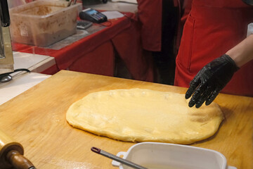 chef prepare dough for traditional czech bakery trdelnik, national pastry food on street Christmas market