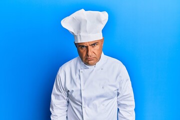Mature middle east man wearing professional cook uniform and hat skeptic and nervous, frowning...