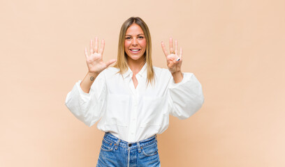 young pretty woman smiling and looking friendly, showing number nine or ninth with hand forward,...