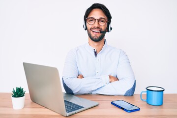 Handsome hispanic man working at the office wearing operator headset happy face smiling with...