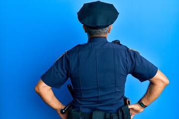 Handsome middle age mature man wearing police uniform standing backwards looking away with arms on body