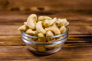 Glass bowl with raw cashew nuts on a wooden table