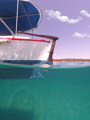 Underwater split photo of traditional wooden fishing boat in Aegean island, with emerald clear sea, Greece