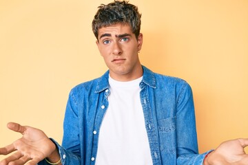 Young handsome man wearing casual clothes clueless and confused expression with arms and hands...