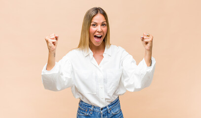young pretty woman feeling happy, positive and successful, celebrating victory, achievements or...