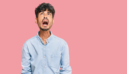 Young hispanic man wearing casual clothes angry and mad screaming frustrated and furious, shouting with anger. rage and aggressive concept.