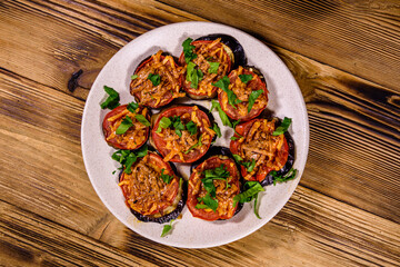 Baked eggplants with tomatoes and cheese in a ceramic plate. Top view