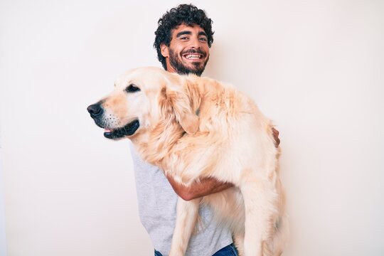 Young handsome man holding and hugging labrador retriever dog, smiling with love to his best friend
