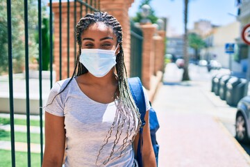 Young african american student woma wearing coronavirus safety mask at the university campus