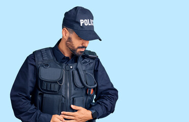 Young hispanic man wearing police uniform with hand on stomach because indigestion, painful illness feeling unwell. ache concept.