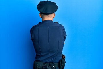Middle age handsome man wearing police uniform standing backwards looking away with crossed arms