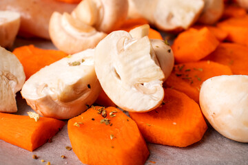 Sliced vegetables close-up. Carrots and mushrooms in pieces on parchment paper. Close-up photo of food.