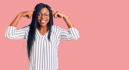 Young african american woman wearing casual clothes and glasses smiling pointing to head with both hands finger, great idea or thought, good memory