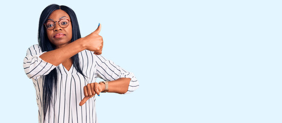 Young african american woman wearing casual clothes and glasses doing thumbs up and down, disagreement and agreement expression. crazy conflict