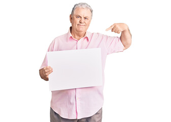 Senior grey-haired man holding blank empty banner pointing finger to one self smiling happy and proud