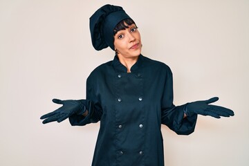 Beautiful brunettte woman wearing professional cook uniform clueless and confused expression with...