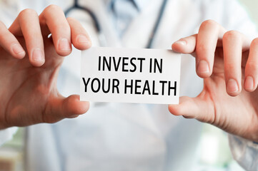 Doctor holding a card with text INVEST IN YOUR HEALTH