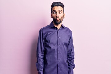 Young handsome man with beard wearing casual shirt making fish face with lips, crazy and comical gesture. funny expression.