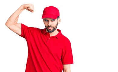 Young handsome man with beard wearing delivery uniform strong person showing arm muscle, confident and proud of power
