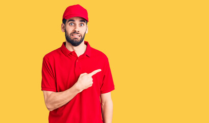 Young handsome man with beard wearing delivery uniform pointing aside worried and nervous with forefinger, concerned and surprised expression