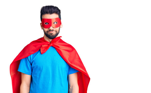 Young handsome man with beard wearing super hero costume smiling looking to the side and staring away thinking.