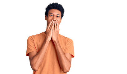 Young african american man wearing casual clothes laughing and embarrassed giggle covering mouth...