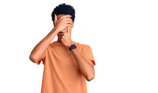 Young african american man wearing casual clothes covering eyes and mouth with hands, surprised and shocked. hiding emotion