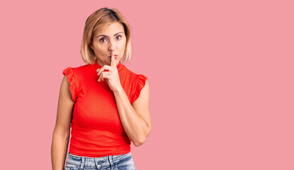 Young blonde woman wearing casual clothes asking to be quiet with finger on lips. silence and secret concept.