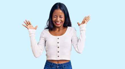 Young indian girl wearing casual clothes celebrating mad and crazy for success with arms raised and...