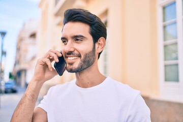 Young hispanic man smiling happy talking on the smartphone at city.