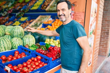 Middle age man with beard smiling happy shopping vegetables at the grocery supermarket