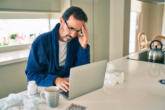Middle age man feeling sick with cold and fever at home, ill with flu disease working from home