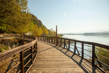 Fototapeta na wymiar Romantic wooden walkway in trees by the lake