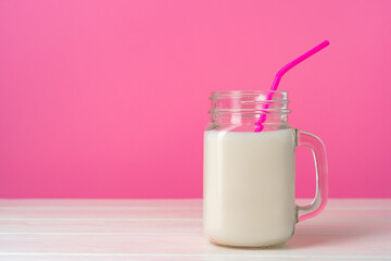 Glassware with fresh milk against pink pastel background