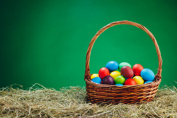 Easter basket with multicolor eggs, green background
