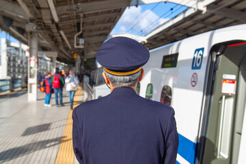 Shinkansen Nozomi Bullet train conductor checks the platform as the train is getting ready to...