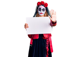 Woman wearing day of the dead costume holding blank empty banner with open hand doing stop sign with serious and confident expression, defense gesture