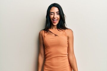 Beautiful hispanic woman wearing summer dress winking looking at the camera with sexy expression,...