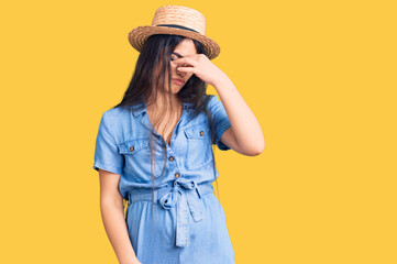 Brunette teenager girl wearing summer hat tired rubbing nose and eyes feeling fatigue and headache. stress and frustration concept.