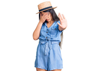 Brunette teenager girl wearing summer hat covering eyes with hands and doing stop gesture with sad and fear expression. embarrassed and negative concept.