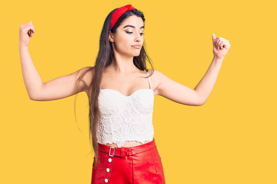 Brunette teenager girl wearing elegant look showing arms muscles smiling proud. fitness concept.