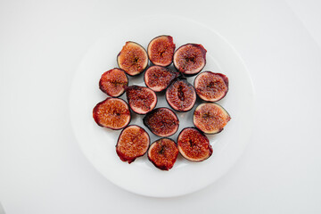 Ripe and sweet figs cut and arranged in a plate on a white background with free space. Fruits and vegetarianism