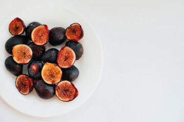 Ripe and sweet figs cut and arranged in a plate on a white background with free space. Fruits and vegetarianism