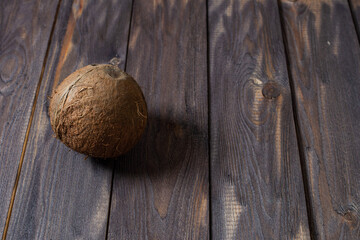 Whole coconut and copy space. Not a large brown coconut on a dark wooden surface of an old table, with space for text, top view.