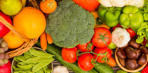 Group vegetables and Fruits Apples, grapes, oranges, and bananas in the wooden basket with carrots, tomatoes, guava, chili, eggplant, and salad on the table.