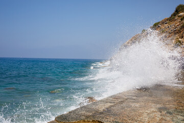 Sea water beats against rocky rocks and makes waves with foam