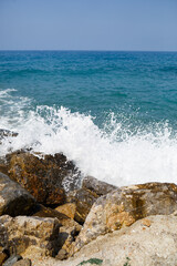 Sea water beats against rocky rocks and makes waves with foam