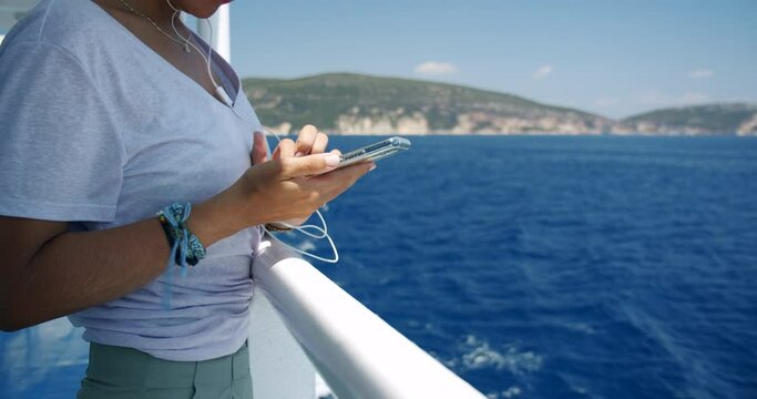Woman using her smart phone on travel by cruise ship. Close up shot of woman's hands with mobile phone.