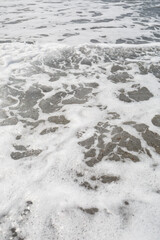 Sea water from a wave with foam on the seashore